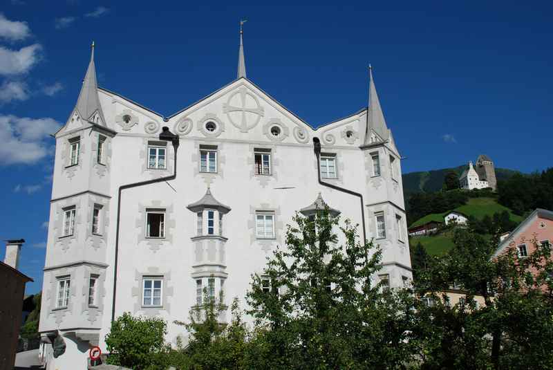 Das Fuggerhaus ins Schwaz hat eine besondere Form, die Erker ragen exzentrisch in den Himmel, hinten ist die Burg Freundsberg zu sehen