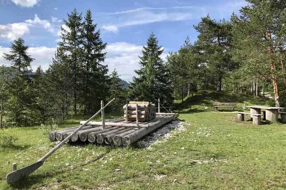 Das große Floß am Isar-Natur-Erlebnisweg, die Kinder spielen hier, Eltern sitzen im Schatten auf der Bank