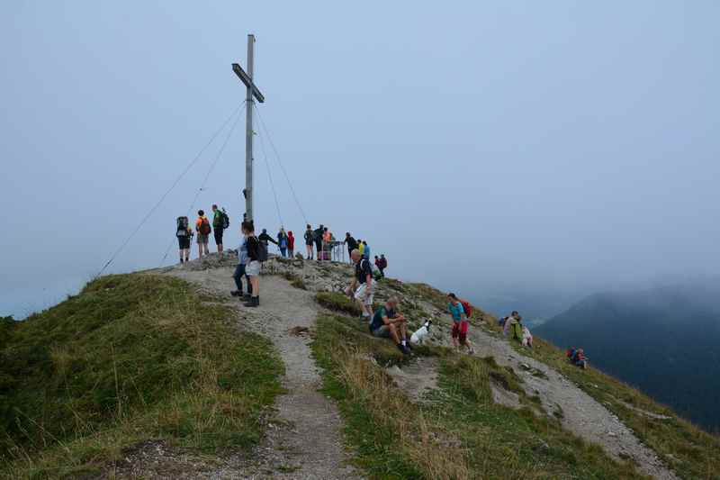 Selbst bei schlechtem Wetter triffst du auf der Jochberg Wanderung Leute am Gipfel