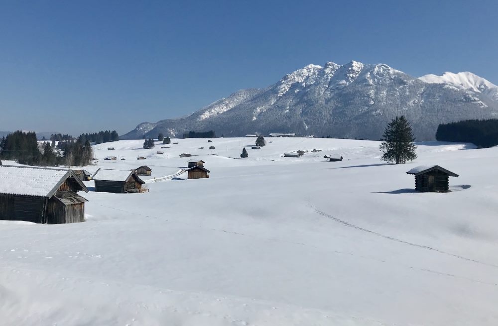 Über die verschneiten Buckelwiesen wandern, vorbei an den Holzstadeln samt Karwendelblick