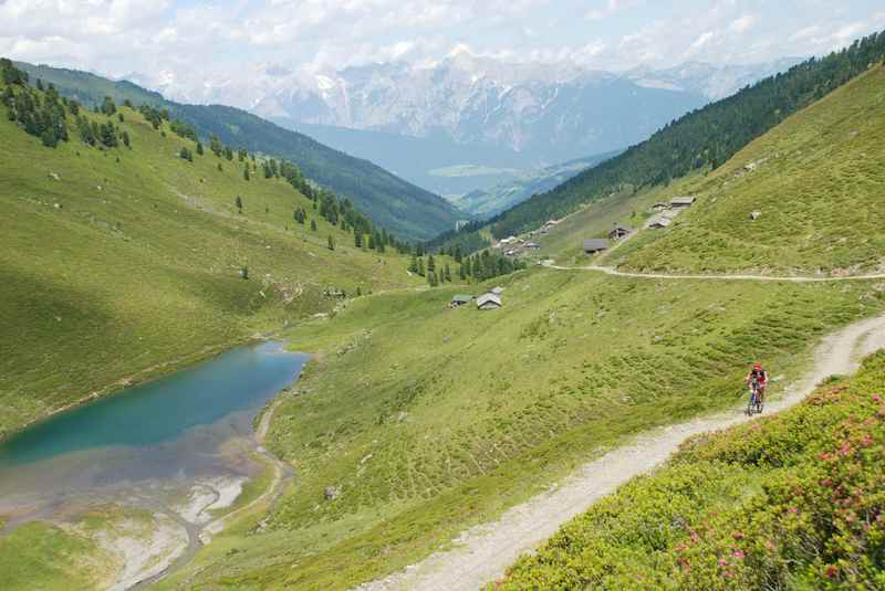 Der Nafingsee von oben gesehen: Mit der Weidener Hütte, der Nafingalm und dem Karwendel; ein Mountainbiker fährt auf der Transalp Etappe