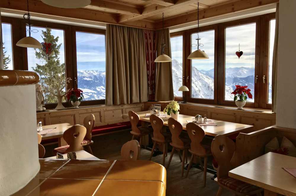 Neben dem warmen Kamin stehen die gemütlichen Tische mit Blick auf die Berge