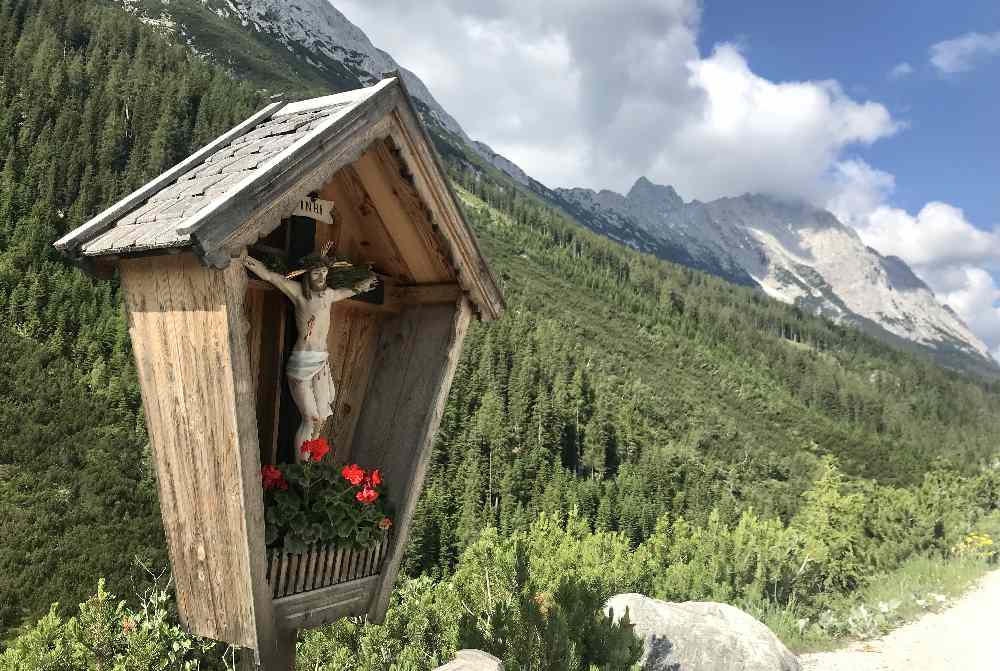 Bei diesem Bildstock siehst du hinter dir das Karwendel, links das Mieminger Gebirge und rechts das Wettersteingebirge